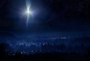 A conceptual photo montage, meant to represent the town of Bethlehem and the Christmas star in the night sky the evening that Christ was born. Horizontal with copy space.